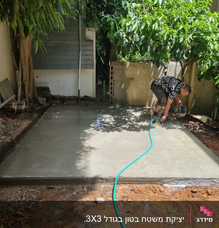 אדם משקה בטון טרי עם צינור גינה